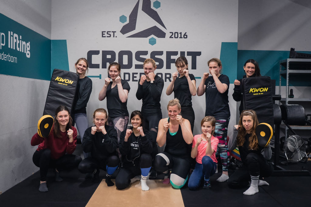 Eine Gruppe Frauen posiert mit ihren Fäusten in Kampfhaltung nach einem Selbstverteidiungsworkshop der Kampfsportmarke Chinkilla. A group of women pose with their fists in fighting position after a self-defense workshop by the martial arts brand Chinkilla